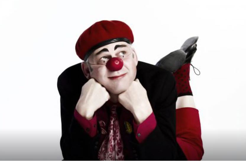 Clown med röd näsa liggande på mage