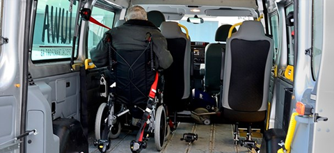 Foto på en person i rullstol som sitter i en rullstolsanpassad minibuss.