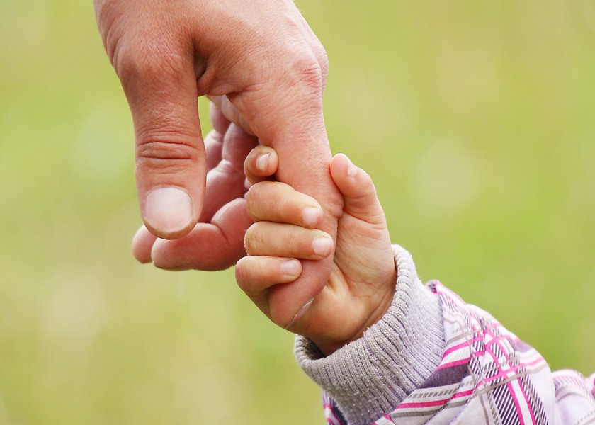 Bild på barnhand som håller i en vuxens hand