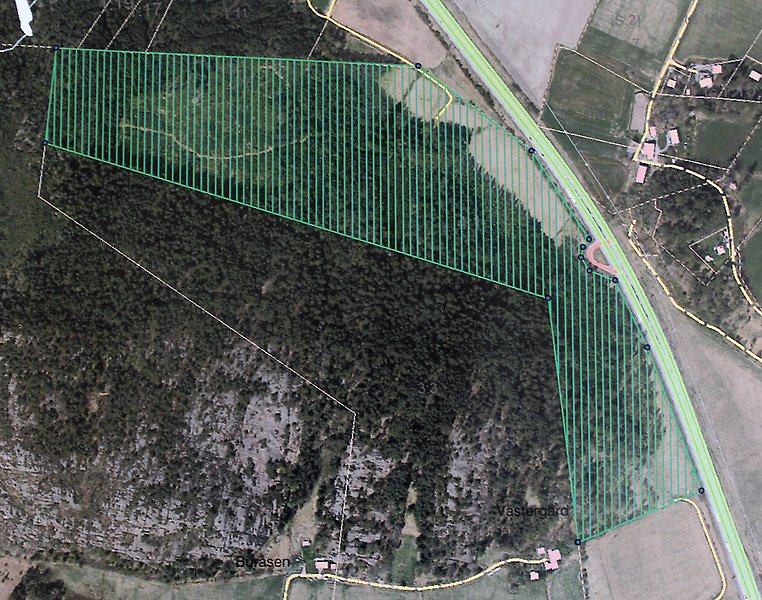 Flygfoto över en skogsfastighet på ett berg omgivet av jordbrukslandskap. Till höger går en motorväg. Området som är till försäljning är markerat med gröna linjer.