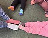 Bild på tre barn och en vuxens fötter med olika sockar på sig.