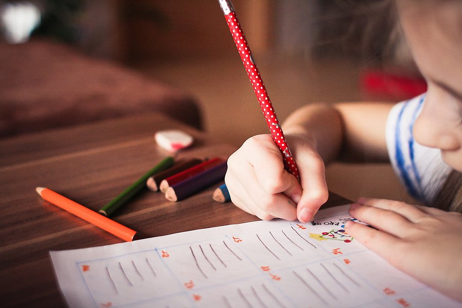 Elev vid bord som skriver med en röd penna