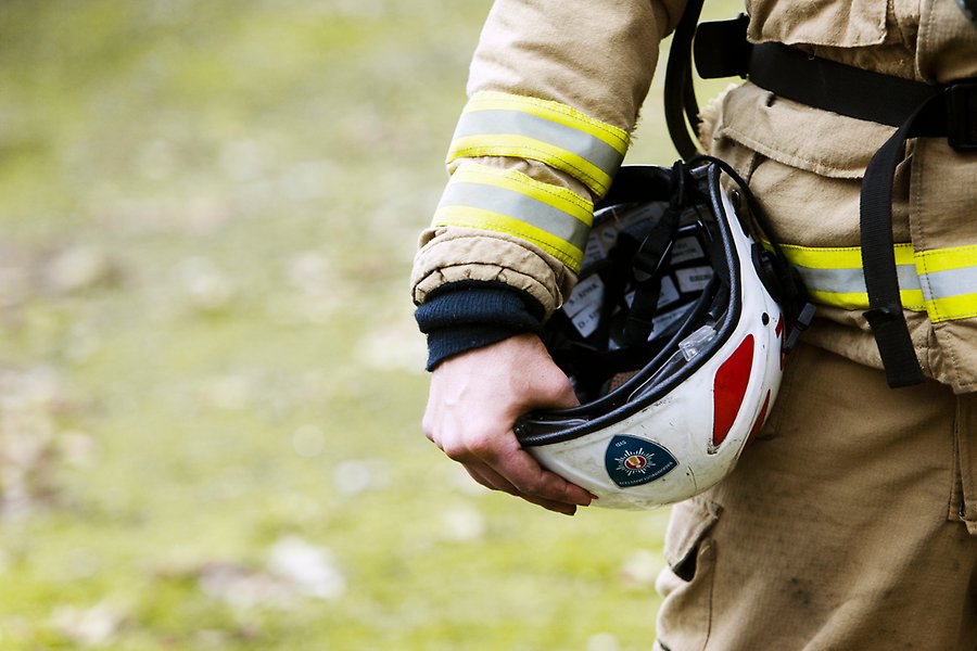 En person i brandmansuniform går mot ett eldhav. Endast personens ben syns på bilden.