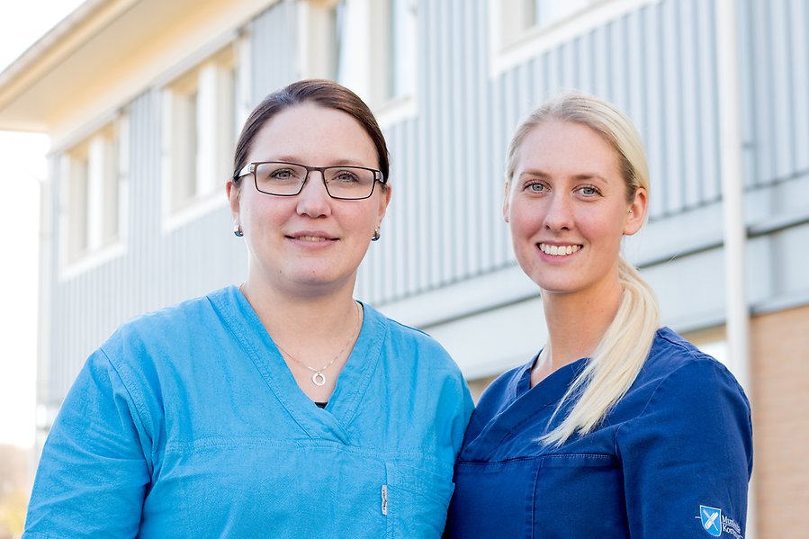 Bild på två sjuksköterskor framför en byggnad