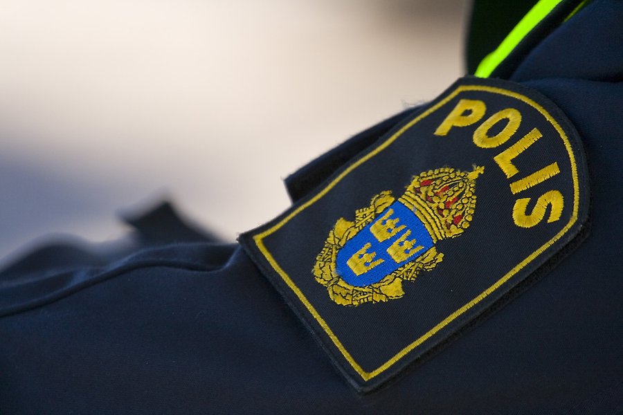 Foto på en arm klädd i en mörkblå polisuniform med polisens gula emblem på armen.