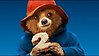 Närbild på en animerad björn i röd hatt och blå kappa som håller en tvåa mellan tassarna.