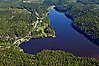 Flygfoto över en sjö som ser ut som ett hjärta omgiven av skog. Längs med sjöns vänstra kan går en landsväg.