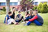 Lärare sitter tillsammans med elever utomhus på en gräsmatta