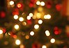 Oskarpt foto på en julgran med julgransljus. Ljusen och julgranskulorna syns som lysande cirklar.