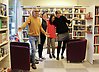 Foto på fyra personer som står tillsammans i ett bibliotek och ler och skrattar in i kameran.