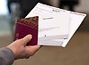Hand som håller i pass, valsedlar och röstkort