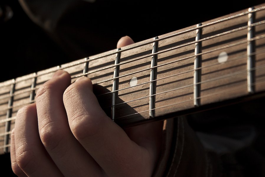 Närbild på en hand när den spelar på en gitarr.