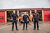 Tre medarbetare i räddningstjänsten framför en brandstation