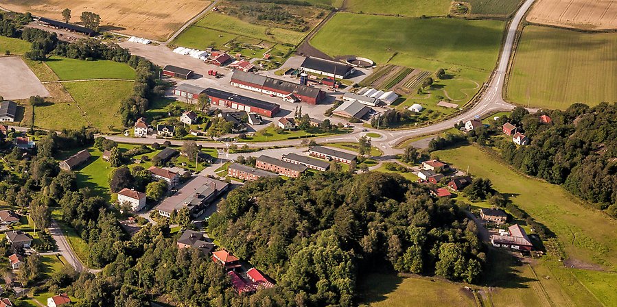 Flygbild över Utvecklingscentrum Munkedal med Kunskapens Hus. Skolan består av flera olika byggnader. Runt skolan är flera åkrar och lite skog.