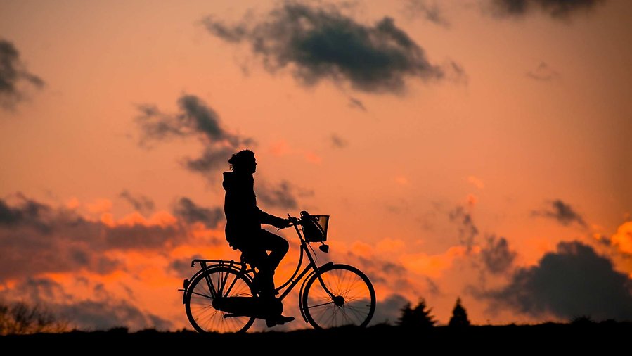 Siluett mot solnedgång av person på cykel