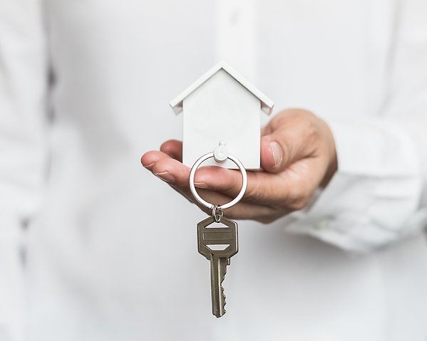 Hand som håller i nyckelring formad som ett hus