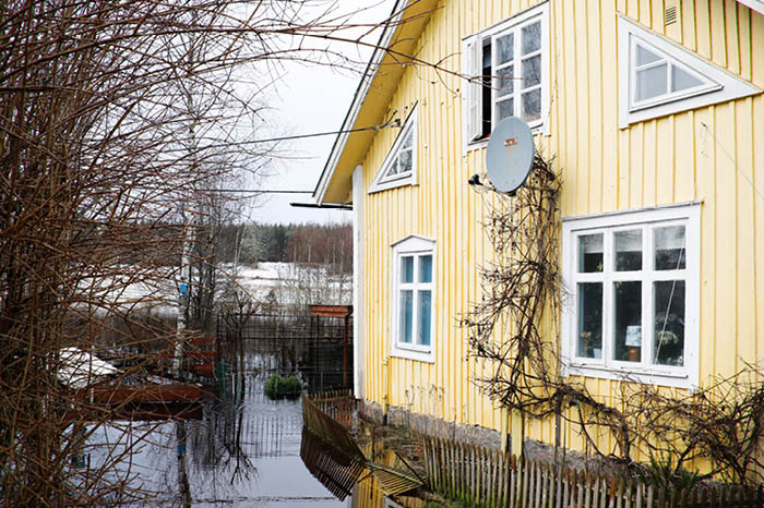 Ett gult hus som är omgärdat av vatten på grund av en översvämning.