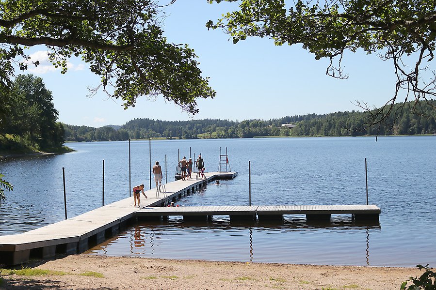 Människor som badar från en badbrygga i Sannesjön.