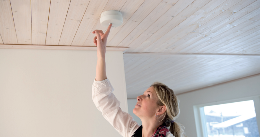 Person som trycker på en brandvarnare.