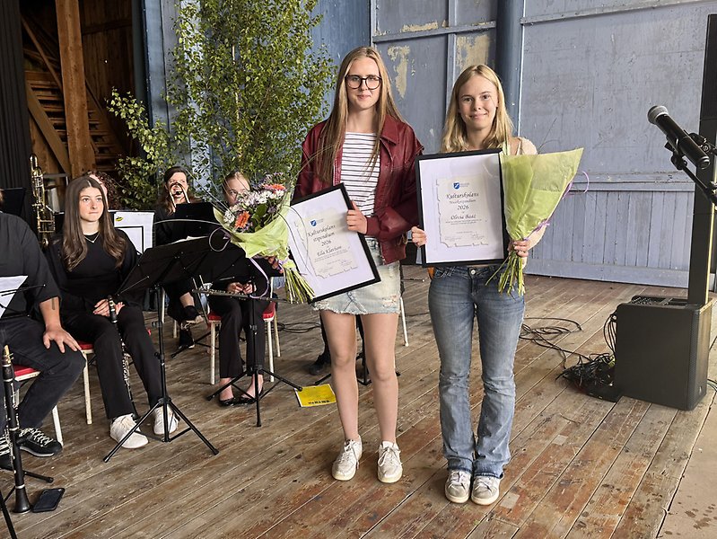 Två tjejer som håller i diplom och blombuketter