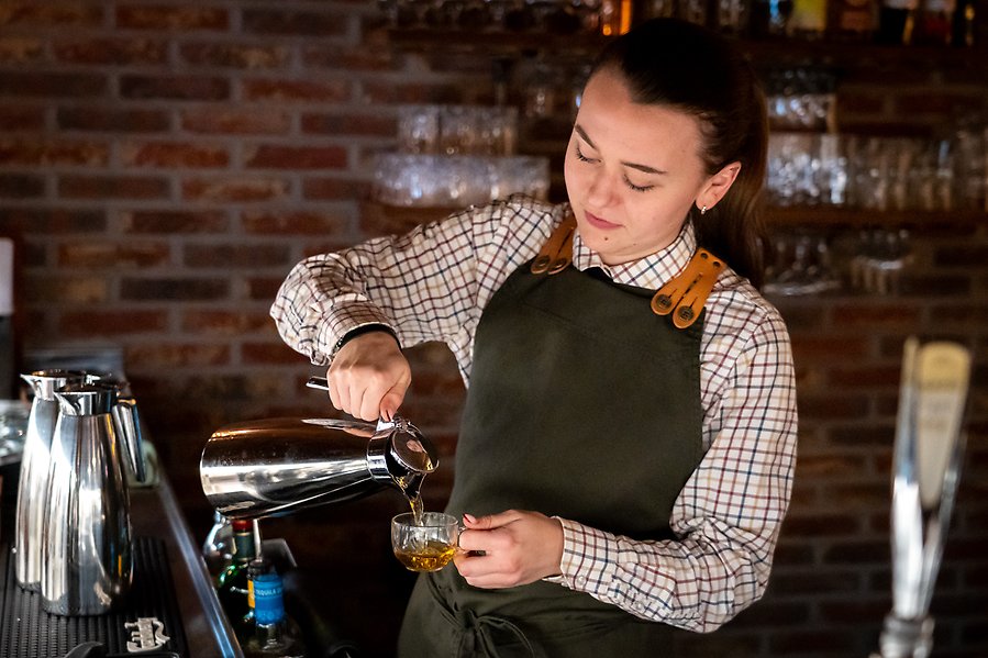 Person i servering häller upp glögg