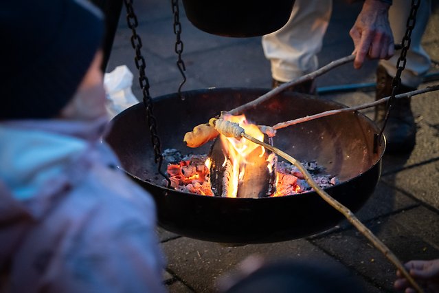 Ett eldfat där några personer grillar pinnbröd.