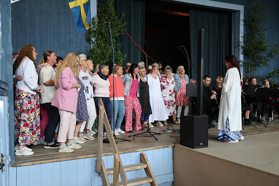 Kör med kvinnor iklädda färgglada kläder sjunger.