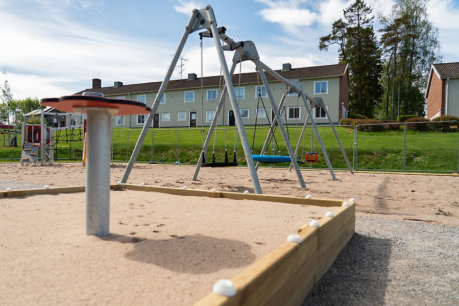 En sandlåda med en gungställning i bakgrunden.