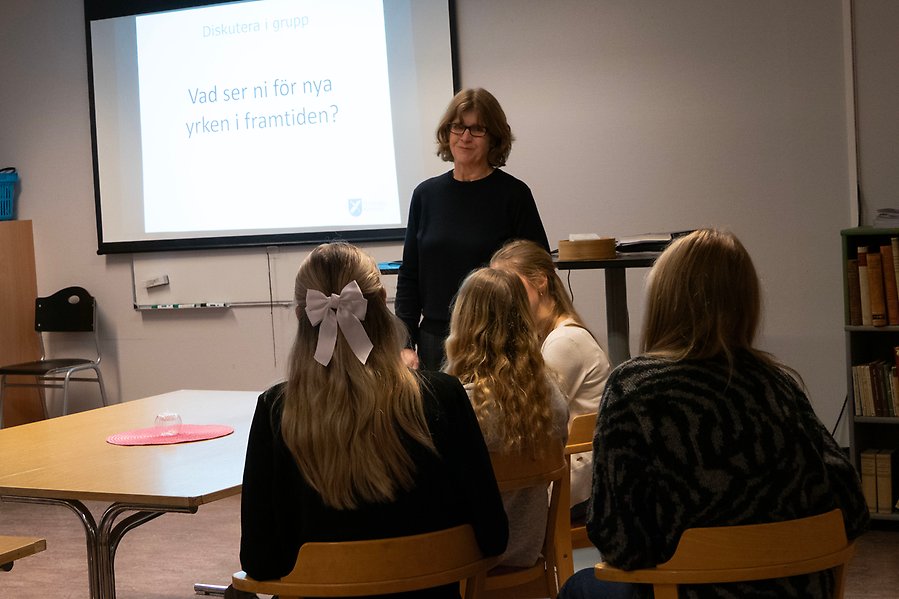 Klassrum där lärare är står i dialog med sittandes elever.