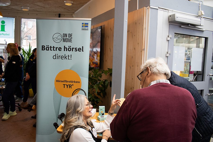 Tre personer står vid en banderoll med texten Bättre hörsel direkt.