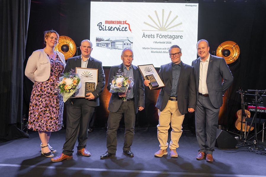 Flera personer på en scen hållandes diplom och blommor