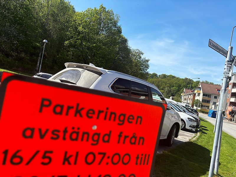 Vägskylt som visar att en parkeringsplats kommer att vara avstängd. I bakgrunden flera parkerade bilar.