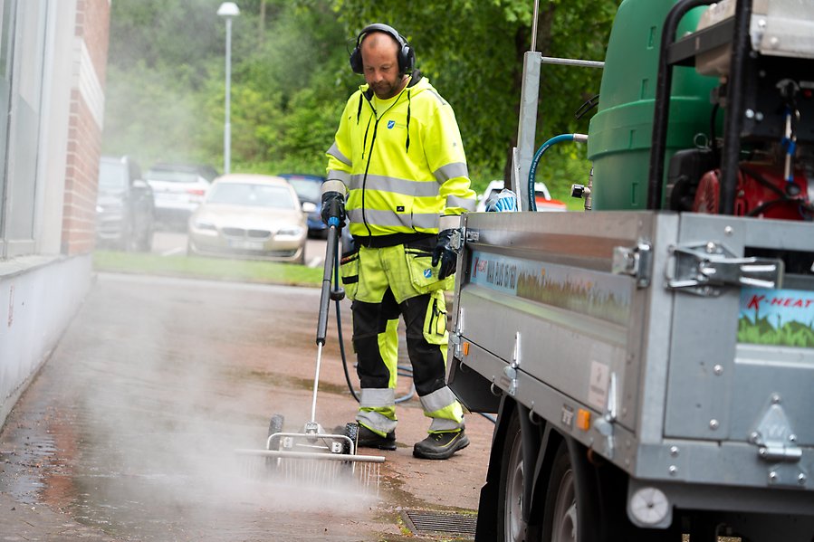 En man som bekämpar ogräs med hjälp av hett vatten som ångar.