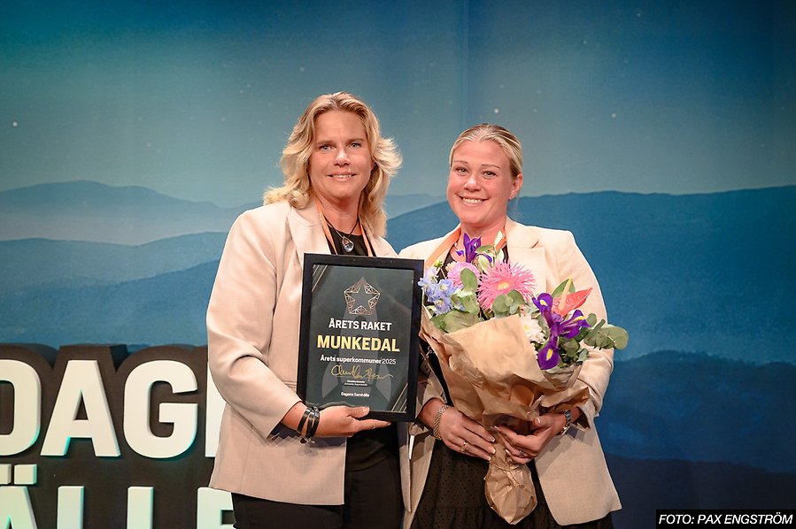 Två glada personer med blommor och diplom i händerna.