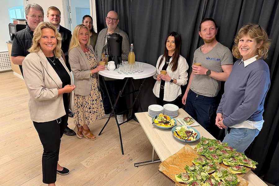 En grupp människor som står vid ett bord och ser glada ut.