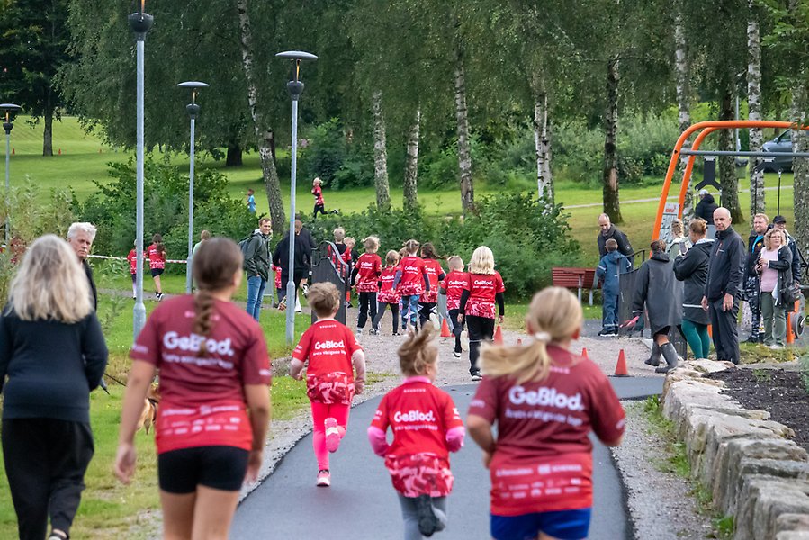 Barn som springer i röda tröjor på en asfalterad väg..