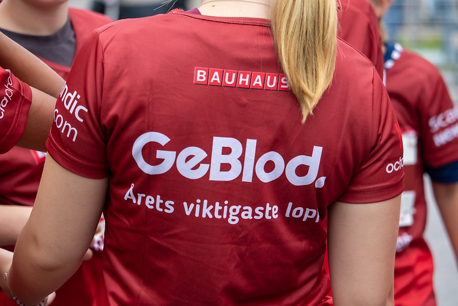 En tjej som har en röd tröja på sig. På ryggen står det Ge blod, årets viktigaste lopp, i vit text.