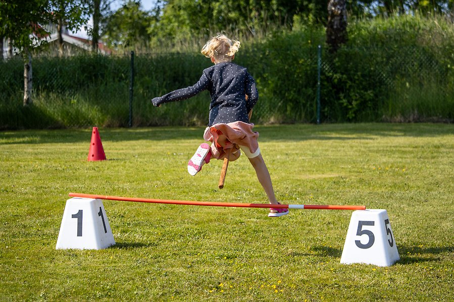 Ung person som hoppar med käpphäst