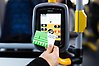 En hand som håller upp ett busskort framför en kortläsare ombord på en buss.