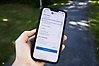 En hand som håller i en smartmobil. På skärmen syns en en app för att anmäla fel och brister på bland annat gator och vägar i kommunen.