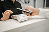 En hand som håller i en mobiltelefon ovanför en betalterminal i en affär.