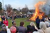 Barn och vuxna står och tittar på en brinnande valborgsbrasa i Munkedals Folkets park på Valborgsmässoafton.