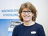 Leende person framför en rollup med texten "Näringslivsutveckling"