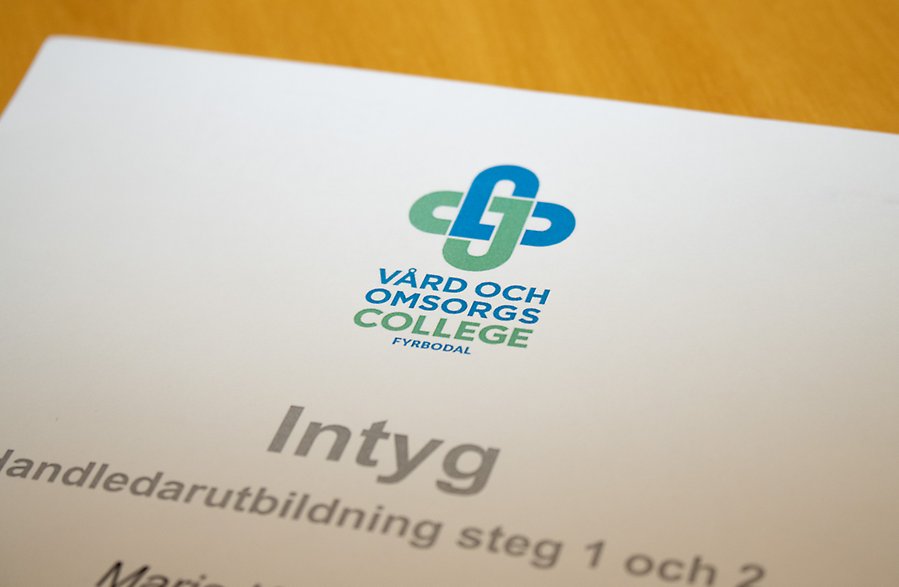 Närbild på ett utbildningsintyg med Vård och omsorgscolleges logotyp