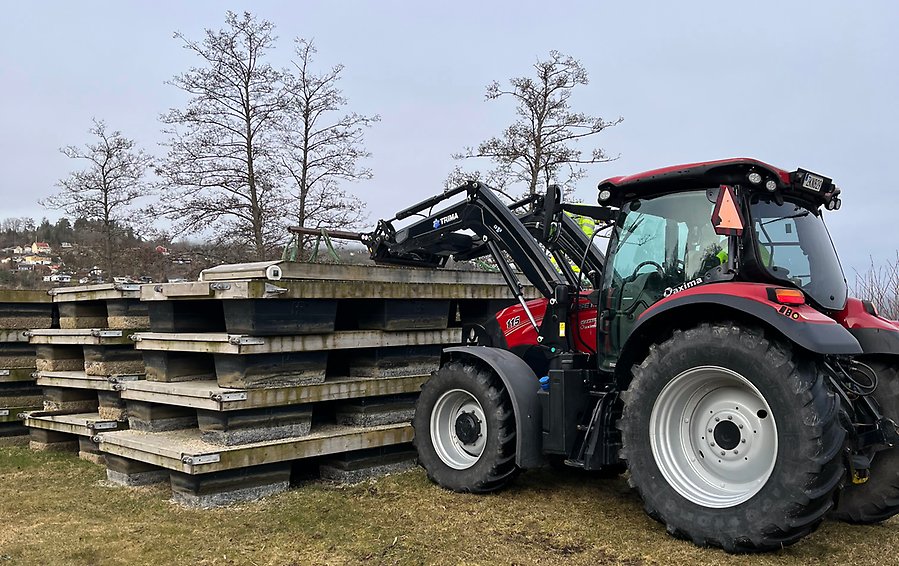 En traktor lyfter av en flytbrygga från en stapel av bryggor.