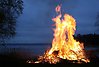 En brasa med höga lågor invid en sjö.