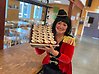 Kvinna i cirkuskostym som håller upp en plåt med muggar med chokladpudding med grädde.